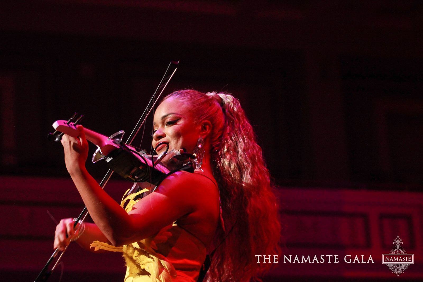 Electric violinist performing on the red-lit gala stage
