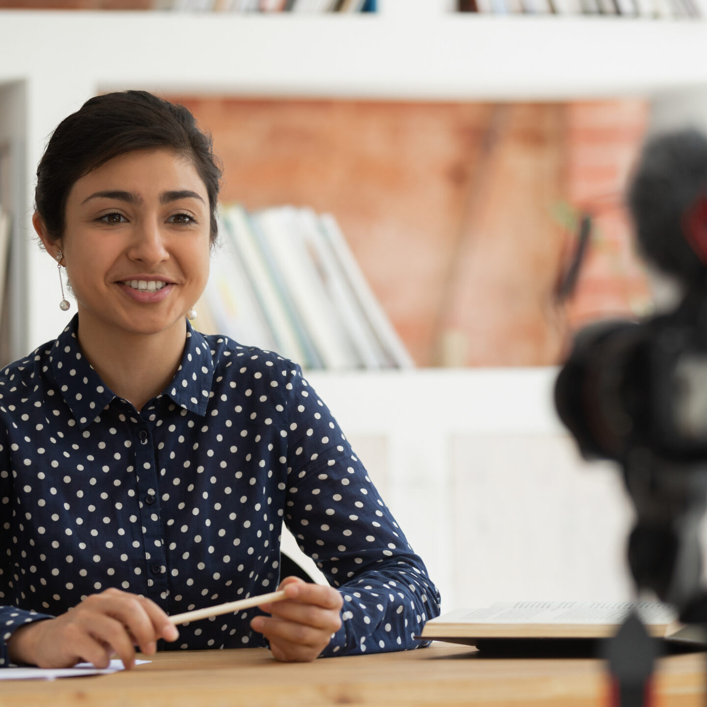 Confident happy indian millennial girl sitting in front of camera, recording self-introduction or educational video for online university course. Smiling business woman sharing professional knowledge.