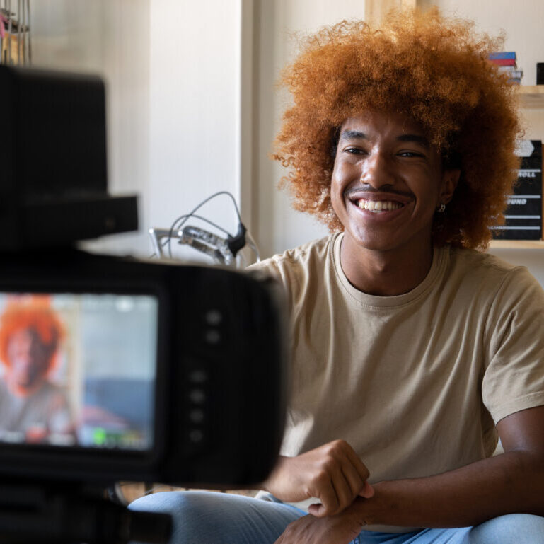 Young African American man recording video for social networks with a camera in an apartment. High quality photo